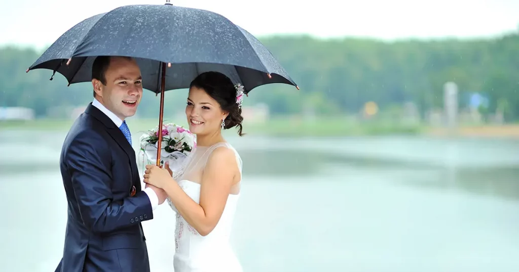 Happy bride and groom in a rainy wedding day hiding from rain