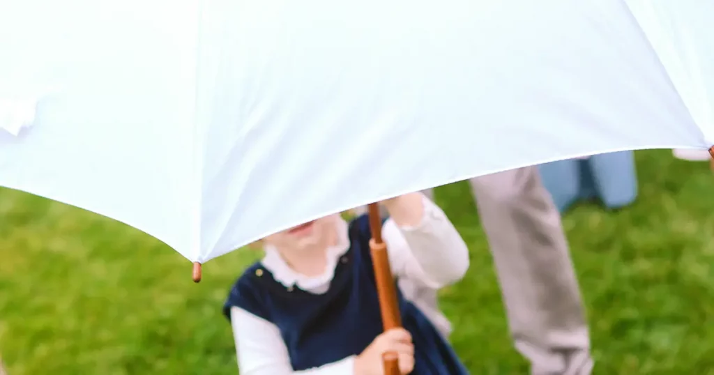 little girl under a white umbrella on a lawn with grass