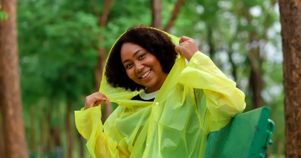Portrait of an African American woman wear yellow raincoat sitting in the rain in the park. On rainy days.