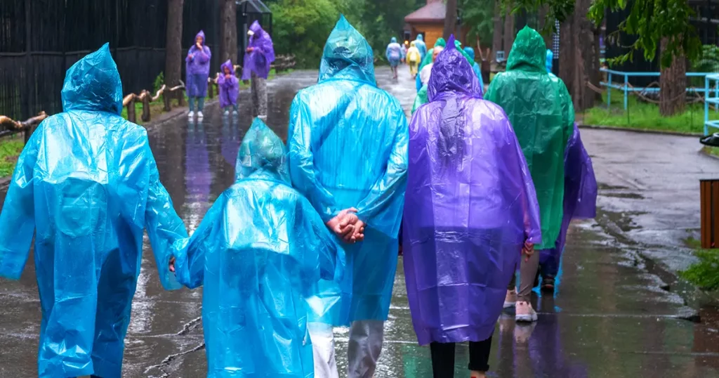 Happy, friendly family in a poncho in the rain for a walk.