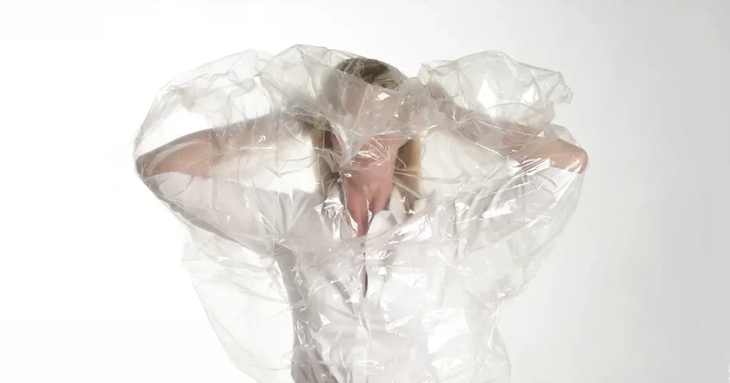 Woman putting on a plastic poncho over her head