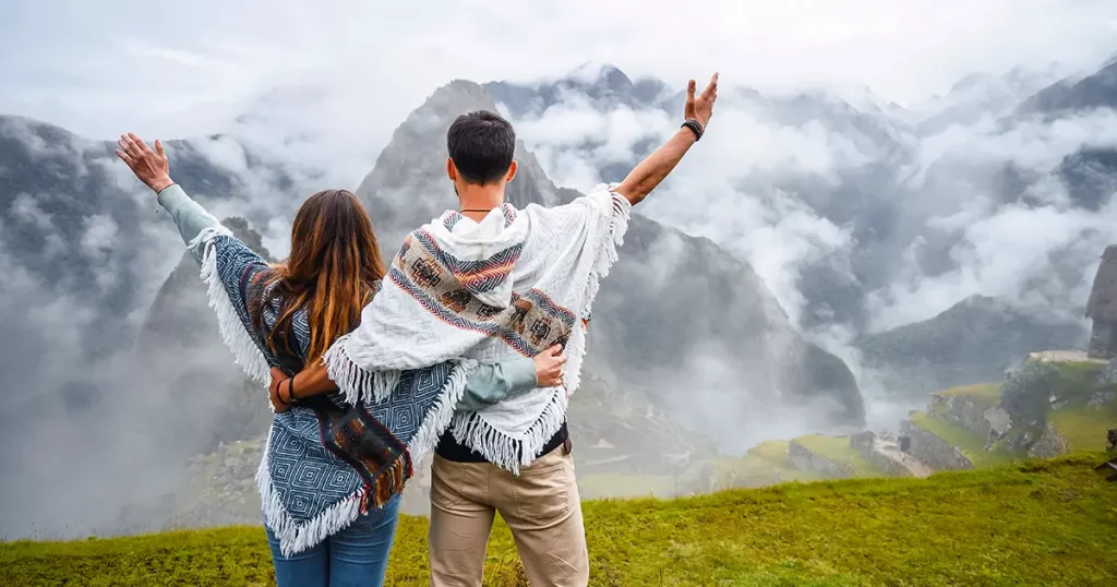 Back view of a caucasian couple wearing the typical peruvian poncho and raising their arms