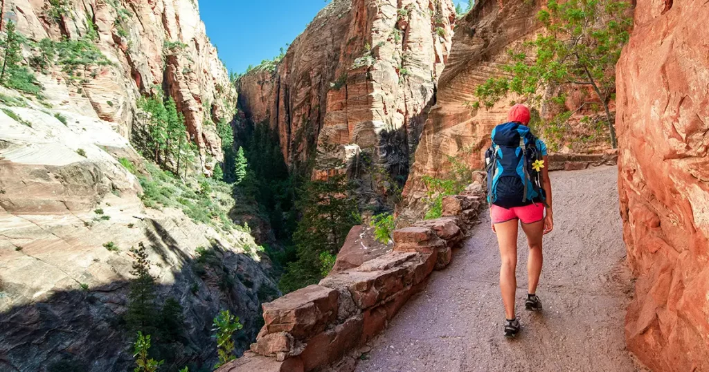 Young woman wearing backpack is trekking to Angel's Landing