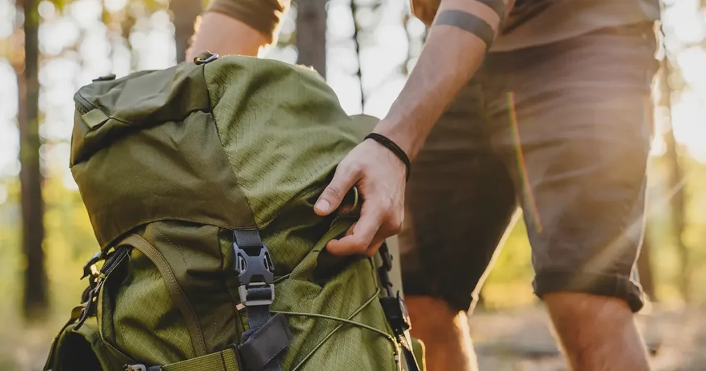 Close up of male hiker holding his camping backpack