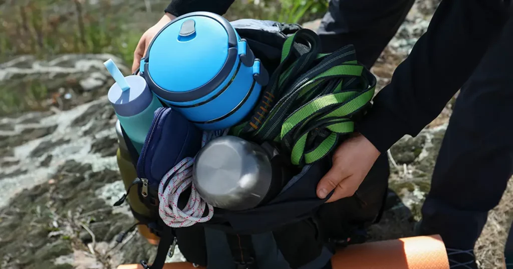 Hiker packing backpack on rocky hill, closeup