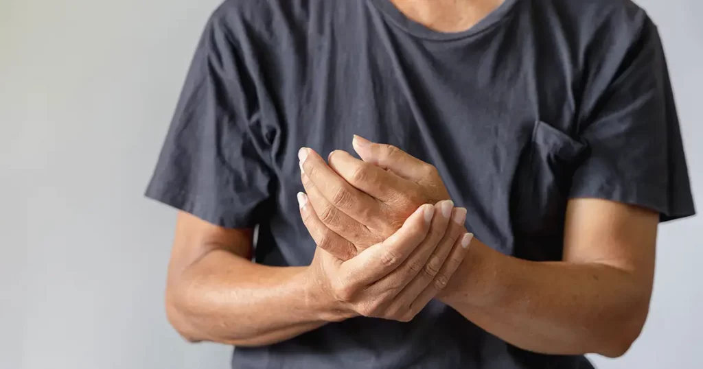 Closeup of Elderly man hands holding his painful wrist caused