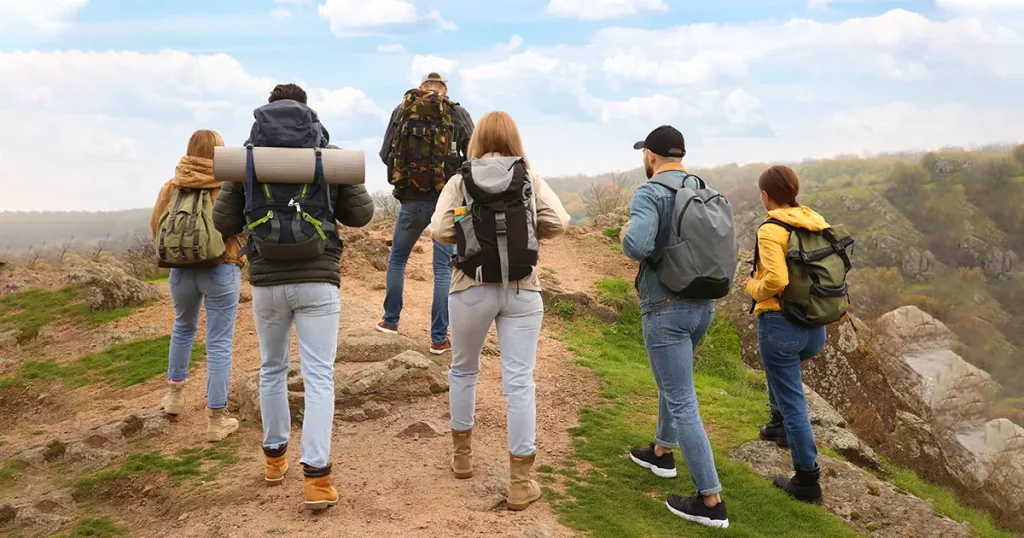 Group of hikers with backpacks climbing up mountains