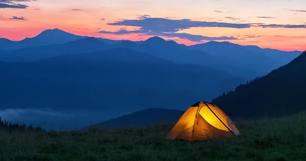 glowing-orange-tent-mountains-under-dramatic
